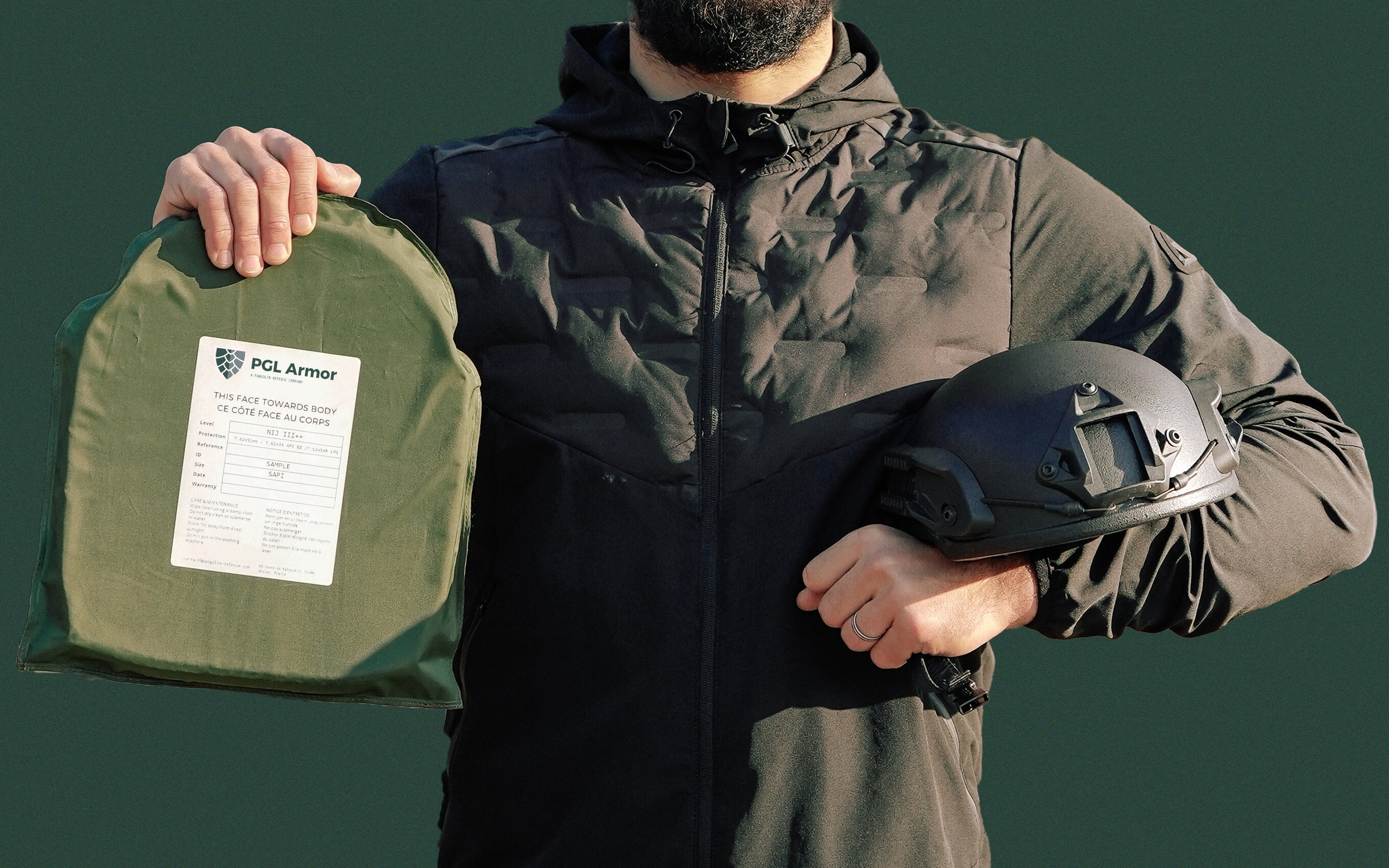 Person holding a PGL Armor ballistic plate and ballistic helmet showing NIJ label