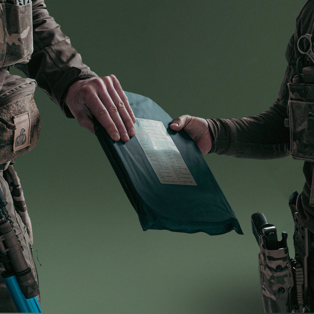 Two operators exchanging a PGL Armor ballistic plate with NIJ label visible