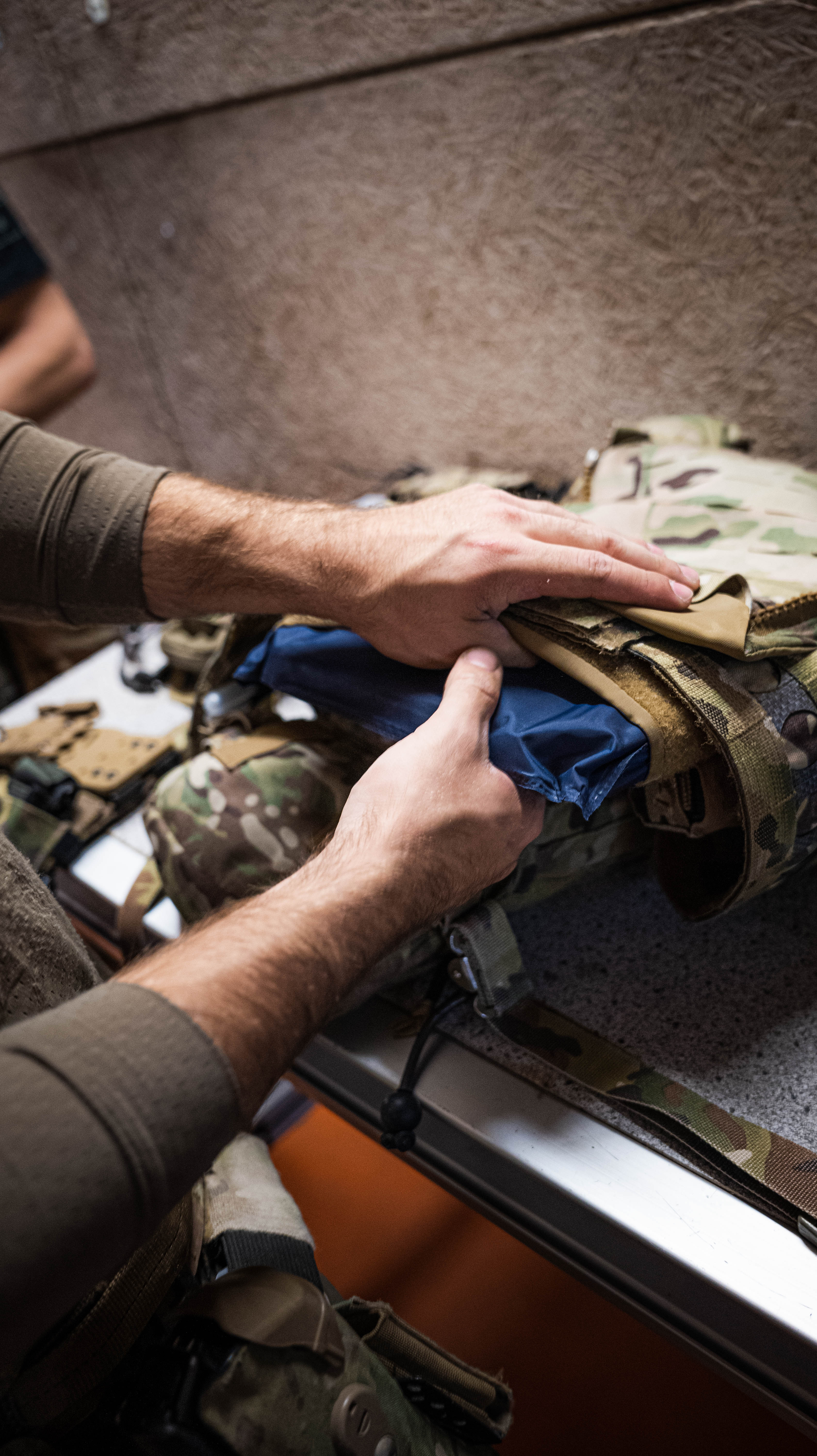 Operator inserting a PGL Armor ballistic plate into camouflage tactical carrier