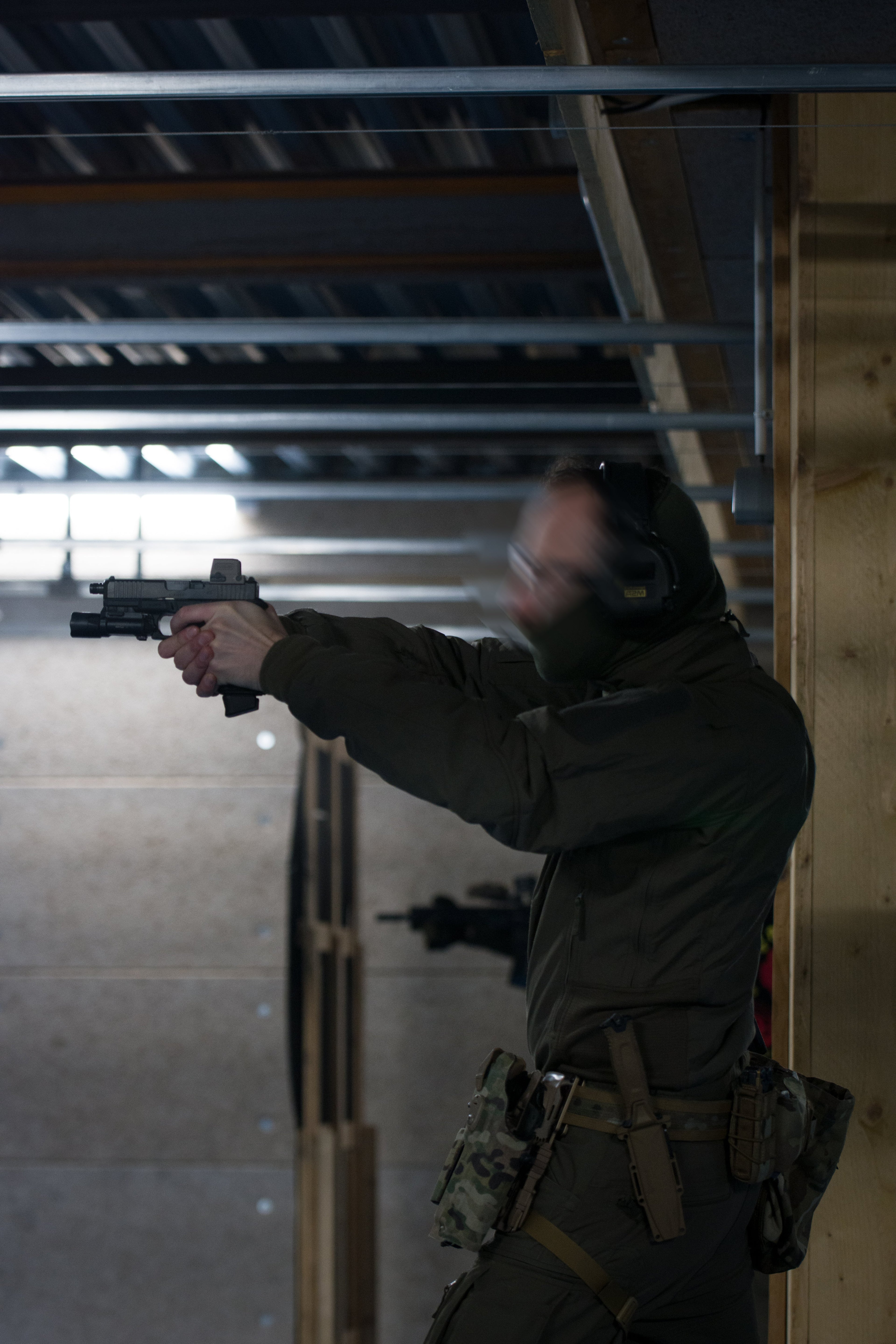Tactical operator aiming handgun during indoor shooting training wearing PGL Armor gear